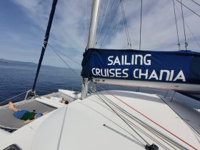 Two guests relax on the nets of a catamaran while sailing in serene waters, perfect for unwinding during a sailing cruise in Chania.
