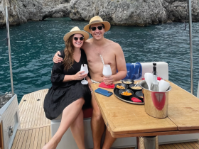 A couple enjoys cocktails and snacks aboard a yacht, capturing a perfect moment of relaxation and celebration on the water.
