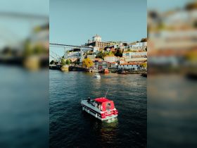 A scenic view of a boat navigating the river with a picturesque city backdrop, showcasing the vibrant architecture and lively atmosphere of the waterfront.