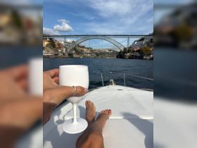A relaxing moment on a boat with a cocktail in hand, showcasing stunning views of a bridge and waterfront scenery — perfect for leisurely outings.