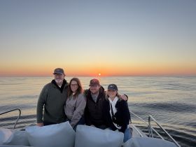 A group of friends enjoys a stunning sunset on the water, capturing a memorable moment aboard their boat — perfect for gatherings and celebrations.
