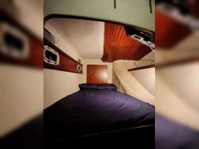 Cozy interior cabin of a boat featuring a comfortable bed and wooden accents, perfect for restful nights on the water.