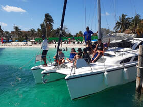 A lively group enjoys a day on a catamaran near the beach, perfect for swimming and fun in the sun.