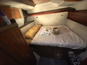 Cozy cabin interior featuring a comfortable bed and decorative touches, perfect for relaxing on a boat getaway.
