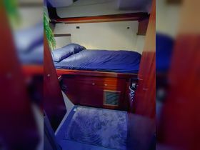 Cozy cabin interior featuring a comfortable bed and wooden furnishings, perfect for relaxing on a boat getaway.