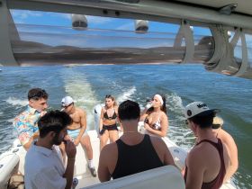 A lively group enjoys a fun day on the water, sipping drinks and soaking up the sun aboard a boat — perfect for summer outings and celebrations.