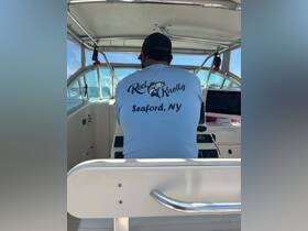 A view from the helm of a boat, showcasing a captain in a blue shirt with 'Reel Knotty' printed on the back, navigating the waters — perfect for fishing charters or boating adventures.