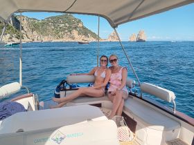 Two friends enjoy a sunny day on a boat, surrounded by stunning coastal scenery — perfect for a relaxing getaway on the water.