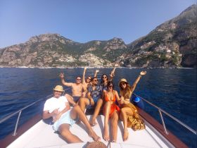 A joyful group of friends celebrates aboard a boat, enjoying the stunning coastal views and sunny weather — perfect for memorable outings on the water.