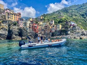 A scenic view of a boat cruising along the stunning coastline of Cinque Terre, with colorful houses perched on the cliffs, perfect for exploring this picturesque region.