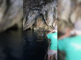 A group enjoys snorkeling in a stunning cave setting, capturing the adventure on camera while surrounded by beautiful rock formations.