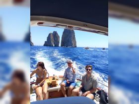 A group of friends enjoys a sunny day on a boat near the iconic rock formations of Capri, surrounded by vibrant blue waters — perfect for a memorable adventure.