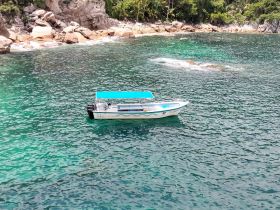 A picturesque view of a boat anchored in clear turquoise waters, surrounded by rocky shores and lush greenery, perfect for exploring coastal destinations.