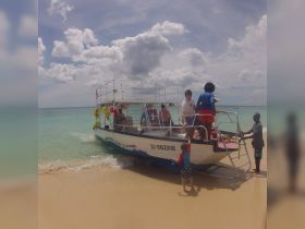 A lively scene at the beach as a group boards a boat, showcasing family fun and adventure on the water.