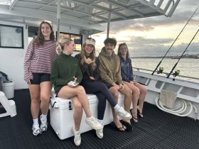 A group of friends enjoys a fishing trip on a boat, showcasing camaraderie and the excitement of a day on the water.