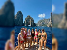 A lively group of friends celebrates a bachelorette party on a boat, enjoying the stunning coastal scenery and each other's company.