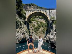 A couple enjoys a scenic boat ride beneath a stunning bridge, surrounded by rocky cliffs and lush greenery — a perfect backdrop for memorable adventures on the water.