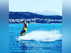 A thrilling moment captured as a man enjoys water skiing in clear blue waters, showcasing the excitement of on-water activities during a sunny day.