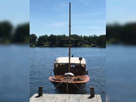 A classic yacht is docked peacefully at the pier, showcasing its elegant wooden structure against a serene water backdrop.