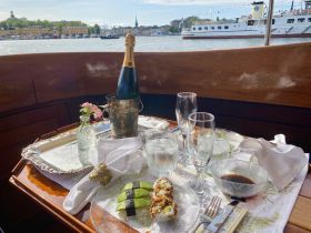 A beautifully arranged dining setup featuring sushi, champagne, and elegant glassware on a boat, perfect for a luxurious dining experience on the water.