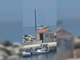 A picturesque view of a sailboat docked near a stone building, showcasing the serene harbor setting perfect for boating enthusiasts.