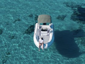 An aerial view of a person relaxing on a boat in crystal-clear waters, showcasing the perfect setting for a tranquil day on the water.