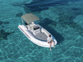 Aerial view of a person relaxing on a boat in crystal-clear waters, showcasing the perfect setting for a day of leisure on the water.