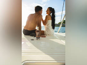 A couple enjoys a romantic moment on a boat, sharing drinks and smiles as the sun sets, perfect for intimate celebrations or getaways on the water.