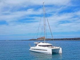 A stunning catamaran anchored in calm waters, showcasing its sleek design against a backdrop of blue skies and gentle waves — perfect for luxury sailing adventures.