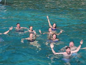 A lively group enjoys a refreshing swim in crystal-clear waters, celebrating together in a fun-filled aquatic adventure.