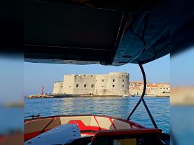 A stunning view from a boat showcasing a historic fortress along the coastline, perfect for sightseeing and exploring the beautiful harbor.