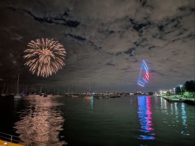 A stunning display of fireworks lights up the night sky over a marina, reflecting beautifully on the water — a perfect backdrop for celebrations and events.
