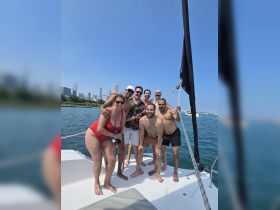 A lively group of friends enjoys a fun day on the water, celebrating together aboard a boat with a stunning city skyline backdrop.