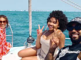 A joyful group of friends poses for a selfie on a sailboat, enjoying a sunny day on the water — perfect for memorable sailing adventures.