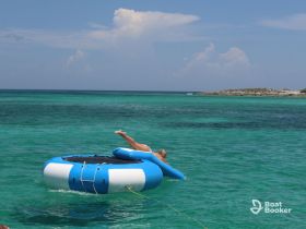 A person enjoys a fun day on a floating mat in the crystal-clear turquoise waters, perfect for summer adventures and relaxation.