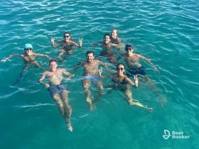 A lively group enjoys a refreshing swim in crystal-clear waters, showcasing the perfect atmosphere for a fun day on the water.