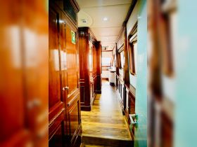 A beautifully designed interior corridor of a luxury boat, featuring polished wood finishes and ample natural light, perfect for a comfortable cruising experience.