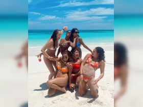 A lively group of friends celebrates on the beach, enjoying drinks and laughter under the sun — perfect for summer getaways and beach parties.