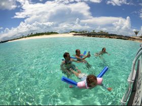 A joyful family enjoys a sunny day swimming in crystal-clear waters, creating unforgettable memories at the beach.