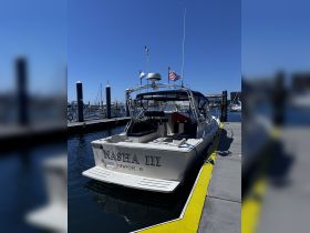 The Nasha III is docked at a marina in Newport, RI, showcasing its sleek design against a clear blue sky.