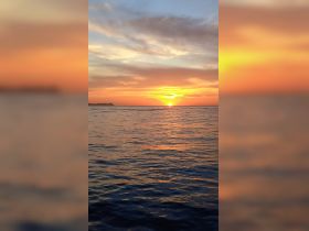 A breathtaking sunset over the ocean, casting vibrant colors across the sky and water — a perfect moment for relaxation and reflection on a boating adventure.