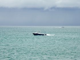 A sleek speedboat navigates through the turquoise waters, showcasing the beauty of a day on the water.