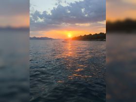 A serene sunset view featuring a boat on calm waters, framed by a picturesque coastline — perfect for capturing the beauty of evening boat rides.