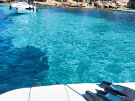 A serene view of clear turquoise waters with a boat in the background, perfect for snorkeling adventures and exploring coastal beauty.