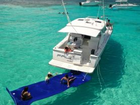 A fun-filled day on the water with friends enjoying a floating mat beside a catamaran, perfect for swimming and relaxation in crystal-clear waters.