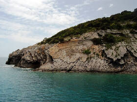 A stunning view of a rocky coastline meeting the turquoise ocean, perfect for showcasing the natural beauty of the area during boat tours.