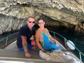 A couple enjoys a moment aboard their boat inside a stunning cave, capturing the essence of adventure and romance on the water.