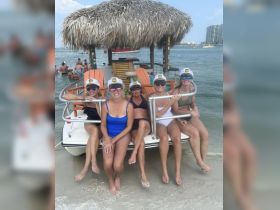 A lively group of friends enjoys a fun day at the beach aboard a pontoon boat, showcasing the perfect setting for celebrations and memorable outings on the water.