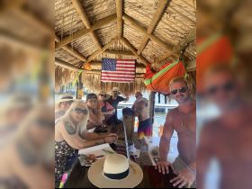 A lively group of friends enjoys drinks and camaraderie at a tropical bar, perfect for celebrating special moments together on the water.
