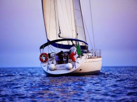 A beautiful sailboat named 'Asia' glides through the tranquil waters, showcasing its elegant design and vibrant flags — perfect for sailing enthusiasts and ocean lovers.